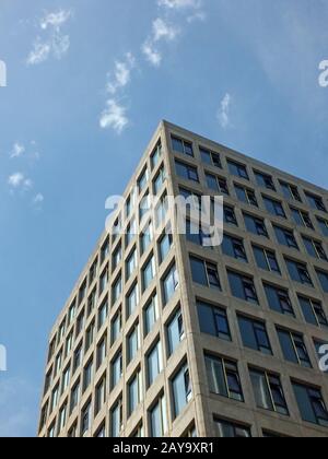 vertical angled corner view of a white high white concrete buildings with sunlit blue sunny sky Stock Photo
