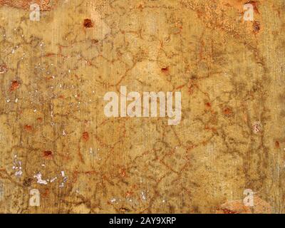 An old rough yellow ochre colored cracked faded stained painted plaster wall texture with red detail Stock Photo