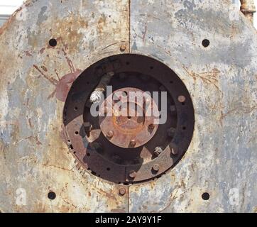 close up full frame detail of old rusting machinery with circular hole in steel plates with bolts Stock Photo