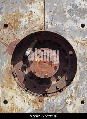 close up full frame detail of old rusting machinery with circular hole in steel plates with bolts Stock Photo