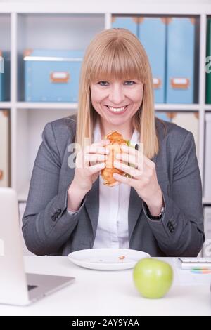 Woman at the office having lunch. Concept for healty or unhealthy food at work. Stock Photo