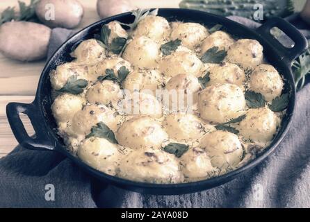 Young potatoes with cottage cheese are baked in the oven. Stock Photo
