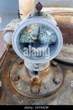 old broken meter mounted on an old rusty abandoned industrial engine with bolts Stock Photo