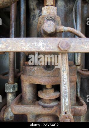 detail of the cylinder and pipes in an old rusted decaying abandoned big petrol engine with bolts pi Stock Photo