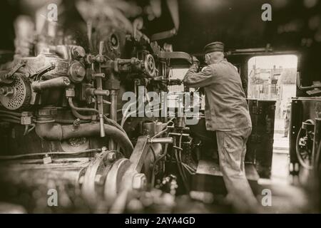 Engine driver working on steam train engine in monochrome Stock Photo