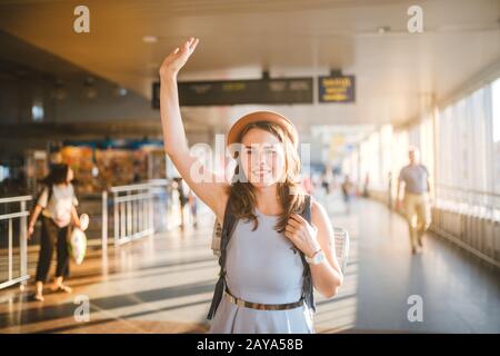 Theme tourism and travel. Young beautiful Caucasian woman in a dress and a hat with a backpack. Tourist mat in the terminal stat Stock Photo