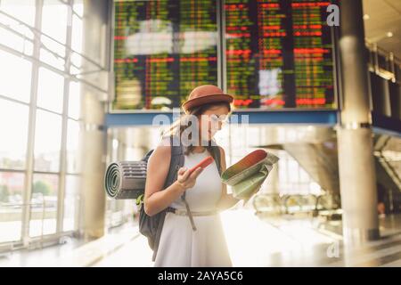 theme travel and transportation. Beautiful young caucasian woman in dress and backpack standing inside train station terminal lo Stock Photo