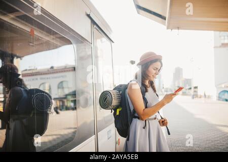 Theme transportation and travel. Portrait young caucasian woman with toothy smile standing train station train background with b Stock Photo