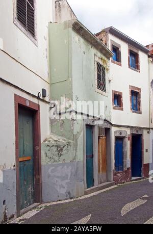 typical quiet empty street in funchal madeira with old traditional houses painted in pastel colors Stock Photo