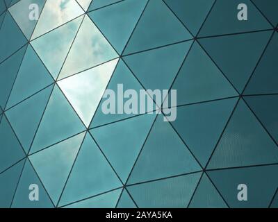 modern corporate building with angular patterned mirrored windows panes reflecting the sky and cloud Stock Photo