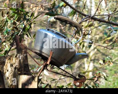 old discarded kettle on top of a gate post in a rural setting surrounded by trees Stock Photo