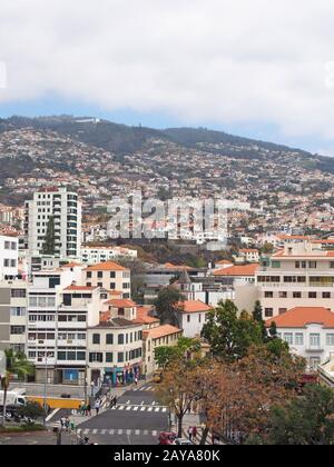 an aerial panoramic view of funchal madeira with people and traffic in the city center and buildings on surrounding hills Stock Photo