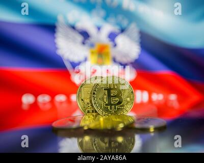 Bitcoin gold coin and defocused flag of background. Virtual cryptocurrency concept. Stock Photo