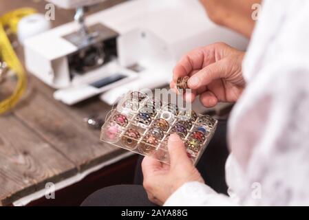 Close up on seamstress hands choosing threads for electrical sewing machine. Stock Photo