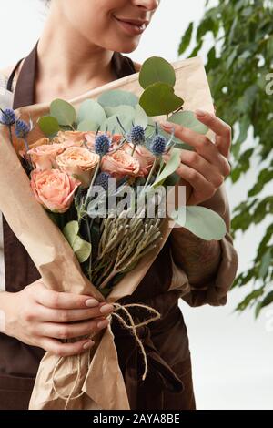 Close-up of greeting flowers bouquet of fresh natural roses living coral color in a florist girl's hands on a white background w Stock Photo