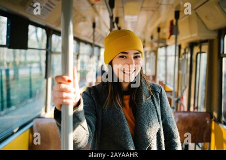 Young woman standing in a wagon of a driving tramway. Transportation, travel and lifestyle concept. Stock Photo