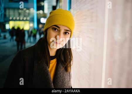 Young woman leans at a illuminated departure plan. Travel,lifestyle and youth concept.