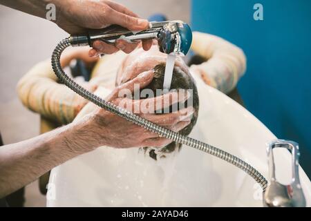 Barbershop theme. Hairdresser for washing hair in a barbershop. Hands male hairdresser close-up washes hair with foam and shampo Stock Photo