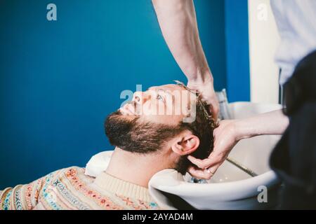Barbershop theme. Hairdresser for washing hair in a barbershop. Hands male hairdresser close-up washes hair with foam and shampo Stock Photo