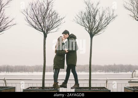 A heterosexual couple young people in love students a man and a Caucasian woman. In winter, in the city square covered with ice, Stock Photo