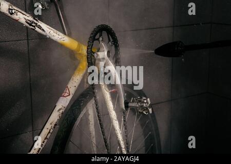 Services professional washing of bicycle in the workshop. Close-up of hand Young Caucasian stylish man doing bicycle cleaning us Stock Photo