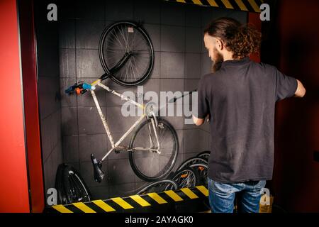 Services professional washing of a bicycle in the workshop. Close-up of hand Young Caucasian stylish man doing bicycle cleaning Stock Photo