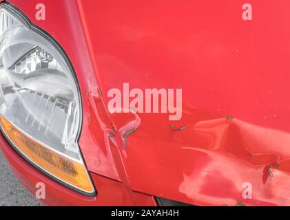 Scratches and rusty dent on front of red car Stock Photo