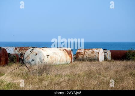 Old abandoned weathered aged corroded fuel tanks on seashore landscape Stock Photo