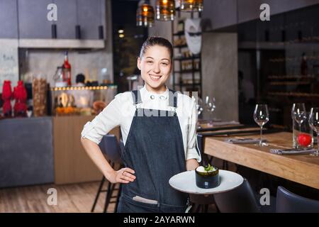 young girl with a beautiful smile a waiter holds in her hands an order sweet dessert dish of Italian cuisine. Dressed in a crust Stock Photo