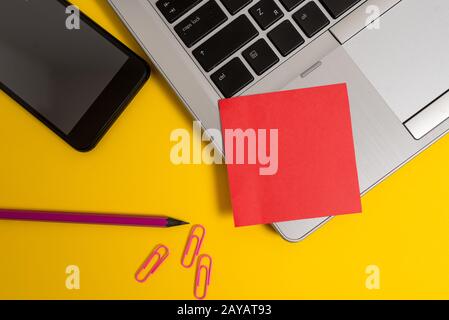Part view trendy metallic laptop blank sticky note smartphone pencil clips colored background. Personal computer small sheet pap Stock Photo