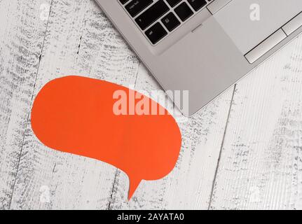 Just corner trendy open laptop blank speech bubble facing downwards lying vintage wooden table. Personal computer resting old ti Stock Photo