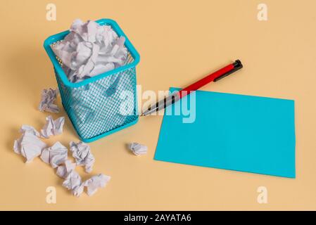 Crumpled paper and stationary in trash can. Note sheet with writing equipment plus scraps placed inside the bin. Office garbage Stock Photo