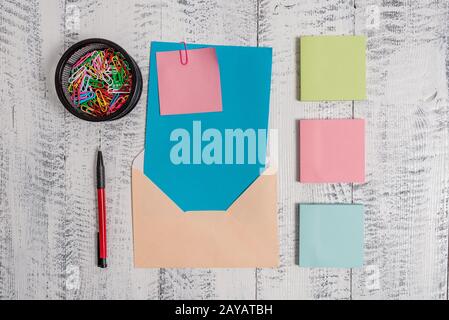 Front view open colored rectangular envelope blank sheet paper sticky note ballpoint clips holder lying retro vintage rustic old Stock Photo