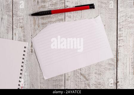 Torn paper and notebook sheet plus a pen placed on top of a wooden table. Papery stationary stick to classic backdrop in tilted Stock Photo