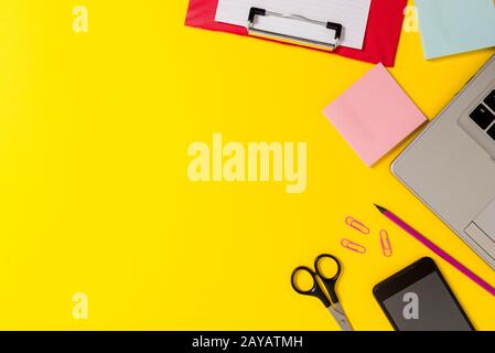 Front view open trendy metallic slim laptop colored clipboard blank paper sheet clips pencil smartphone scissors notepads colore Stock Photo