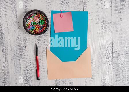 Front view open colored rectangular envelope blank sheet paper sticky note ballpoint clips holder lying retro vintage rustic old Stock Photo