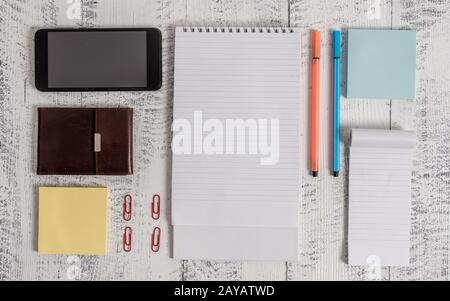 Smartphone, man wallet, sticky notes, clips, spiral notebook, pens ballpoints, notepad lying retro vintage rustic old wooden tab Stock Photo