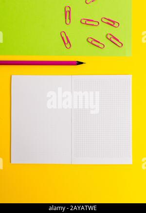 Blank squared notebook colored paper sheet clips pencil highlighter marker ballpoint plain color background. Empty notes importa Stock Photo