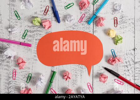 Blank colored speech bubble pens ballpoints clips binders crushed paper balls lying retro vintage rustic old table. Abstract des Stock Photo