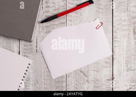 Torn paper and notebook sheet plus a pen placed on top of a wooden table. Papery stationary stick to classic backdrop in tilted Stock Photo