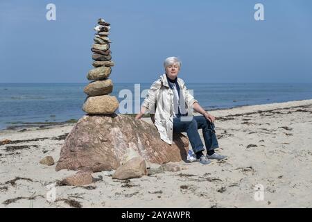 Senior sitting next to a stone pyramid Stock Photo