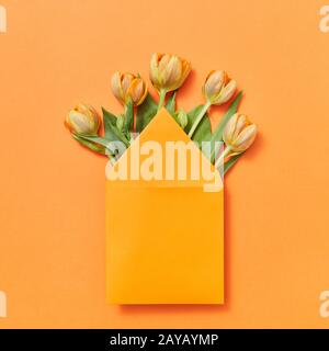Mock up envelope with yellow tulips on an orange background. Stock Photo