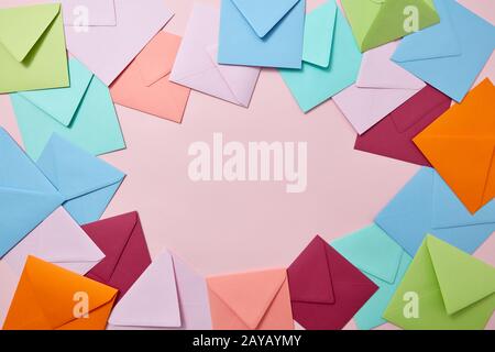 Decorative frame from colorful craft envelopes on a light pink background. Stock Photo