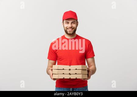 Cheerful young deliveryman holding pizza boxes while isolated on white studio background Stock Photo