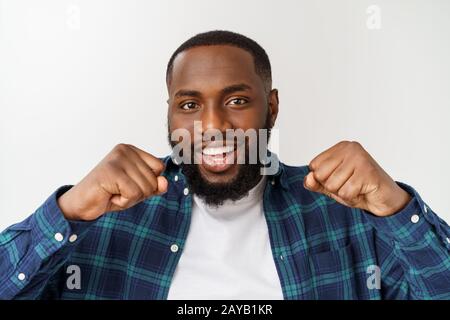 Portrait of a cheerful young man shouting with arms raised in success. Stock Photo