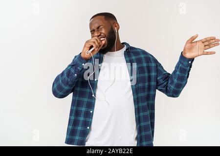 Handsome Afro American man in casual clothes is listening to music using a smart phone and smiling. Stock Photo