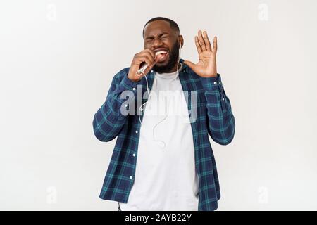 Handsome Afro American man in casual clothes is listening to music using a smart phone and smiling. Stock Photo