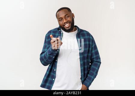 Handsome Afro American man in casual clothes is listening to music using a smart phone and smiling. Stock Photo