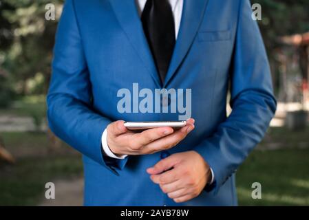 Business concept with man holding mobile phone with touch screen. Businessman holds lap top in his hand. Businessman in blue sui Stock Photo