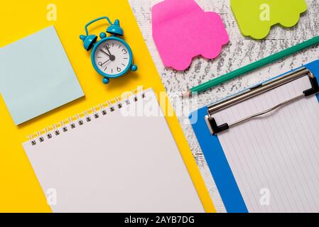Closeup front view blank spiral notepad pencil small alarm clock letter size colored paper sheet car sticky notes pad clipboard Stock Photo